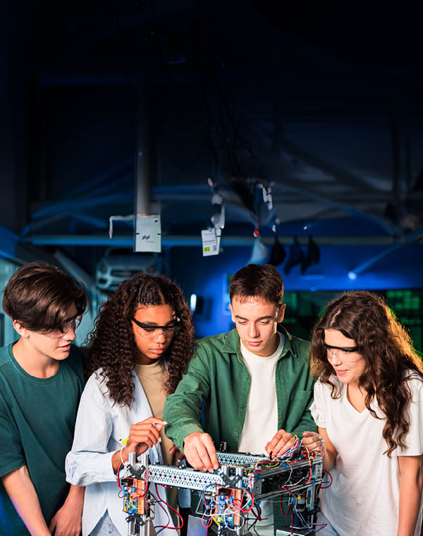Group of young people doing experiments in robotics in a laboratory. Girls in protective glasses